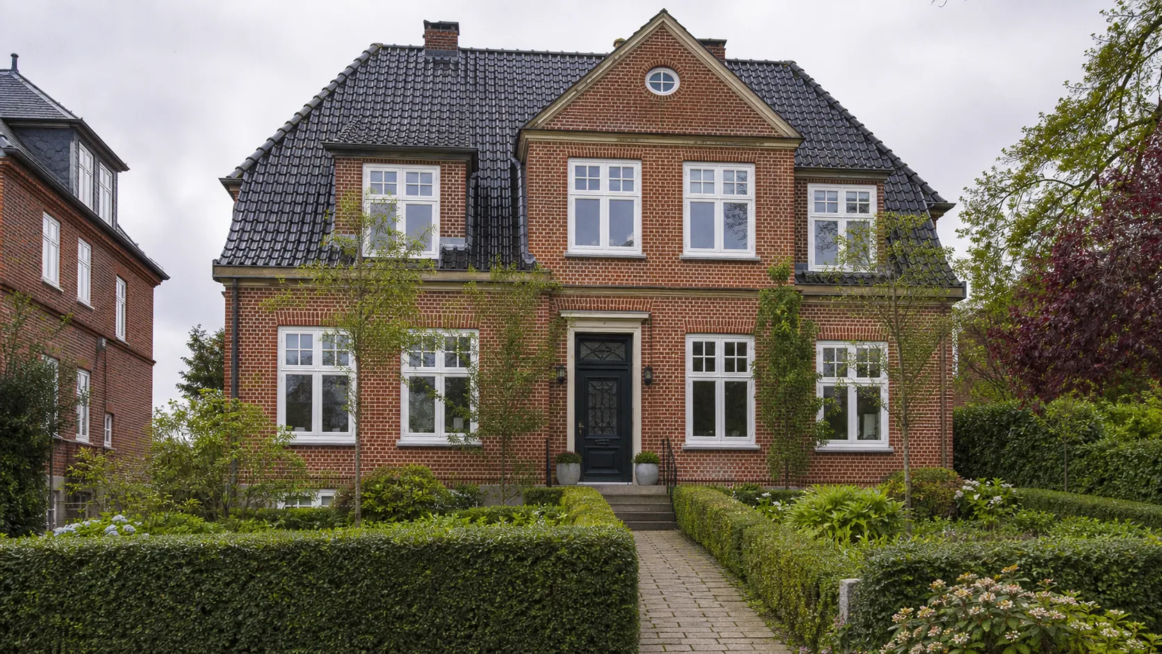 Klassisk dansk murermestervilla med hvide dannebrogsvinduer i rød murstensfacade